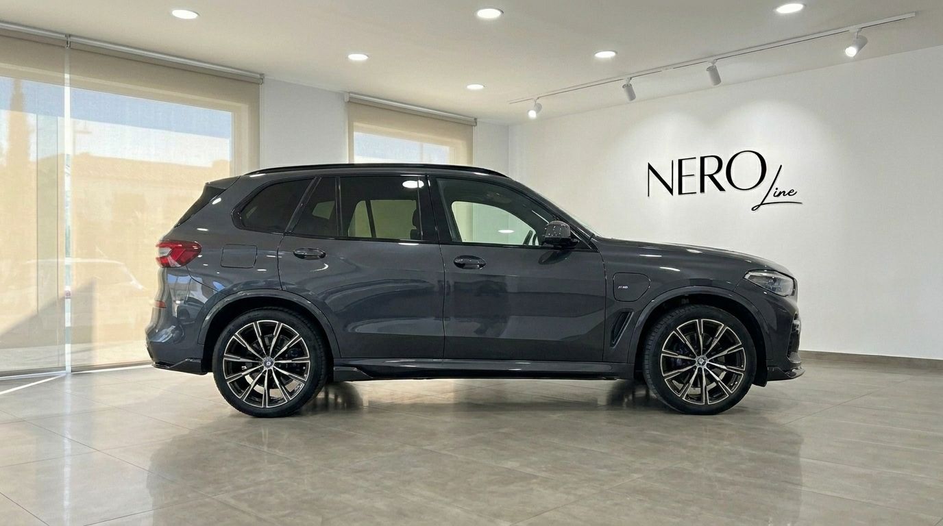 The dark grey BMW X5 xDrive45e is parked in a showroom with the Nero Line logo on the wall in Alicante.