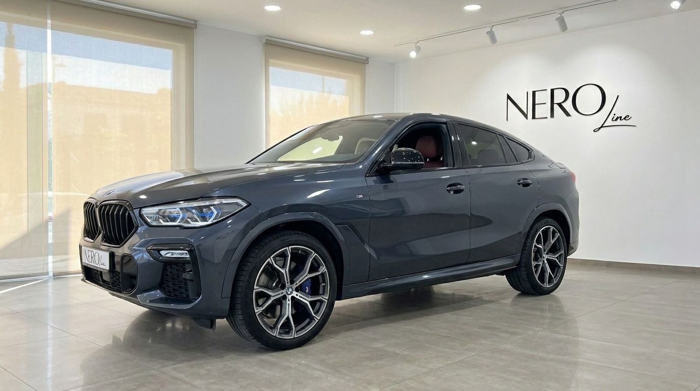 A dark grey 2020 BMW X6 luxury SUV is showcased from a front three-quarter view inside a bright NEROline showroom in Alicante.