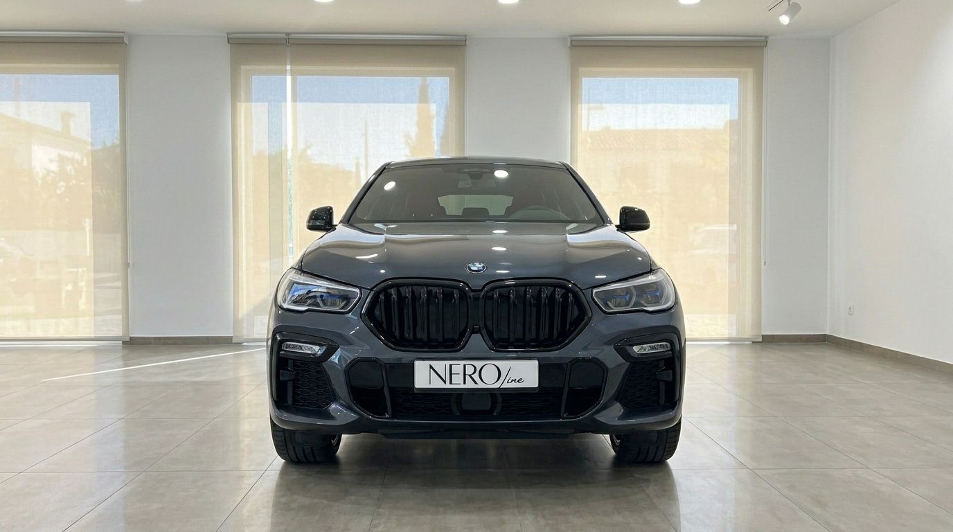The dark grey 2020 BMW X6 is prominently displayed from a direct front view in a showroom in Alicante.