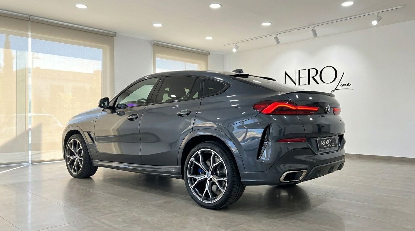 The dark grey BMW X6 is shown from a rear three-quarter angle in a showroom in Alicante.