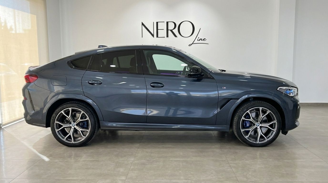 The sleek dark grey 2020 BMW X6 luxury SUV is parked in a showroom, showcasing its side profile in Alicante.