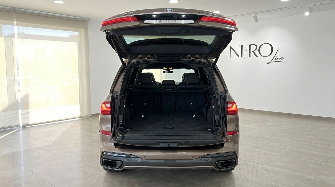 The rear view of the dark olive green 2024 BMW X7 3.0d in Alicante, showcasing its spacious open trunk and luxurious interior.