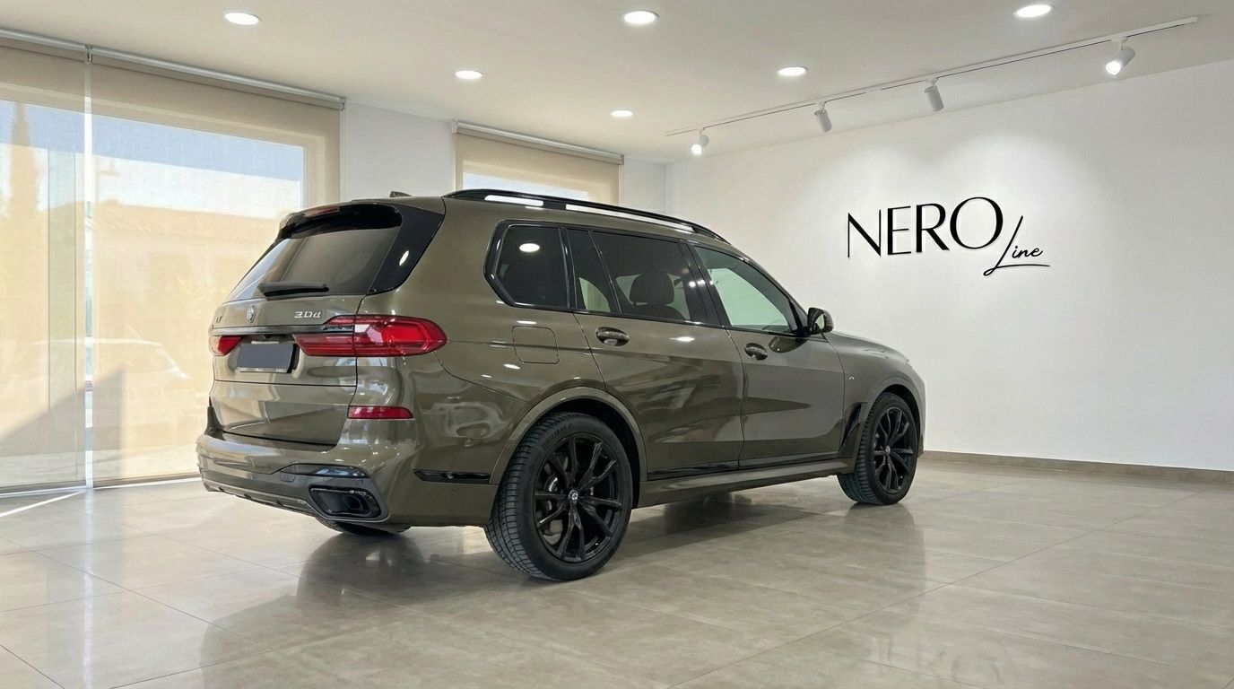 The dark olive green 2024 BMW X7 3.0d is showcased from a rear three-quarter view, parked in a bright showroom in Alicante.