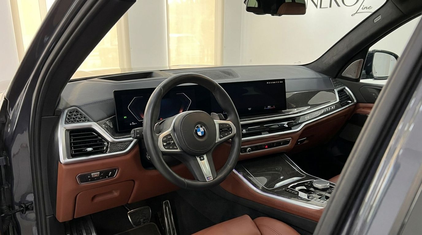 The luxurious interior of the 2025 BMW X7, featuring a modern cockpit with a steering wheel, digital displays, and brown leather accents, available for rent in Alicante.