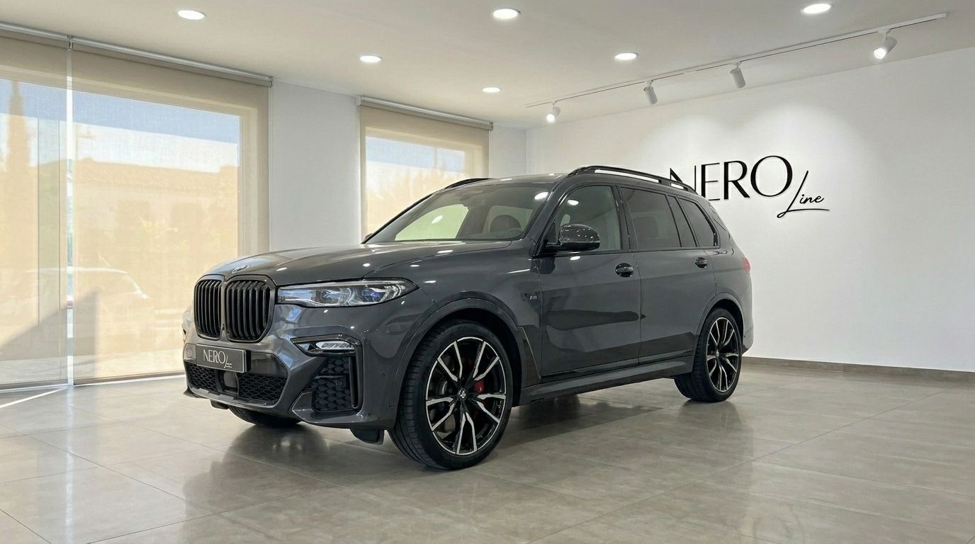 The gloss dark grey 2021 BMW X7 M50i is showcased from a front three-quarter view in a Benidorm showroom.