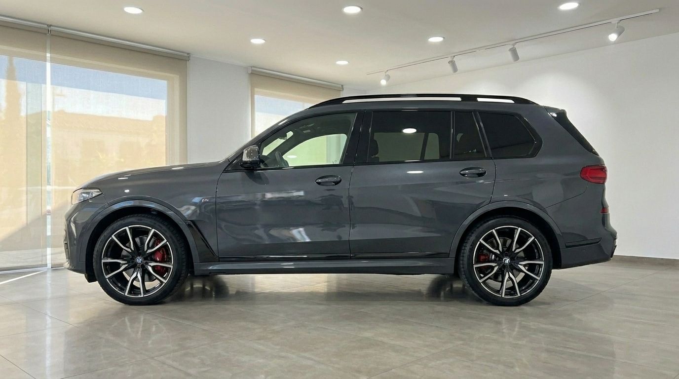 The 2021 BMW X7 M50i in Gloss Dark Grey is shown from its side profile, highlighting its sleek design and large wheels in Benidorm.