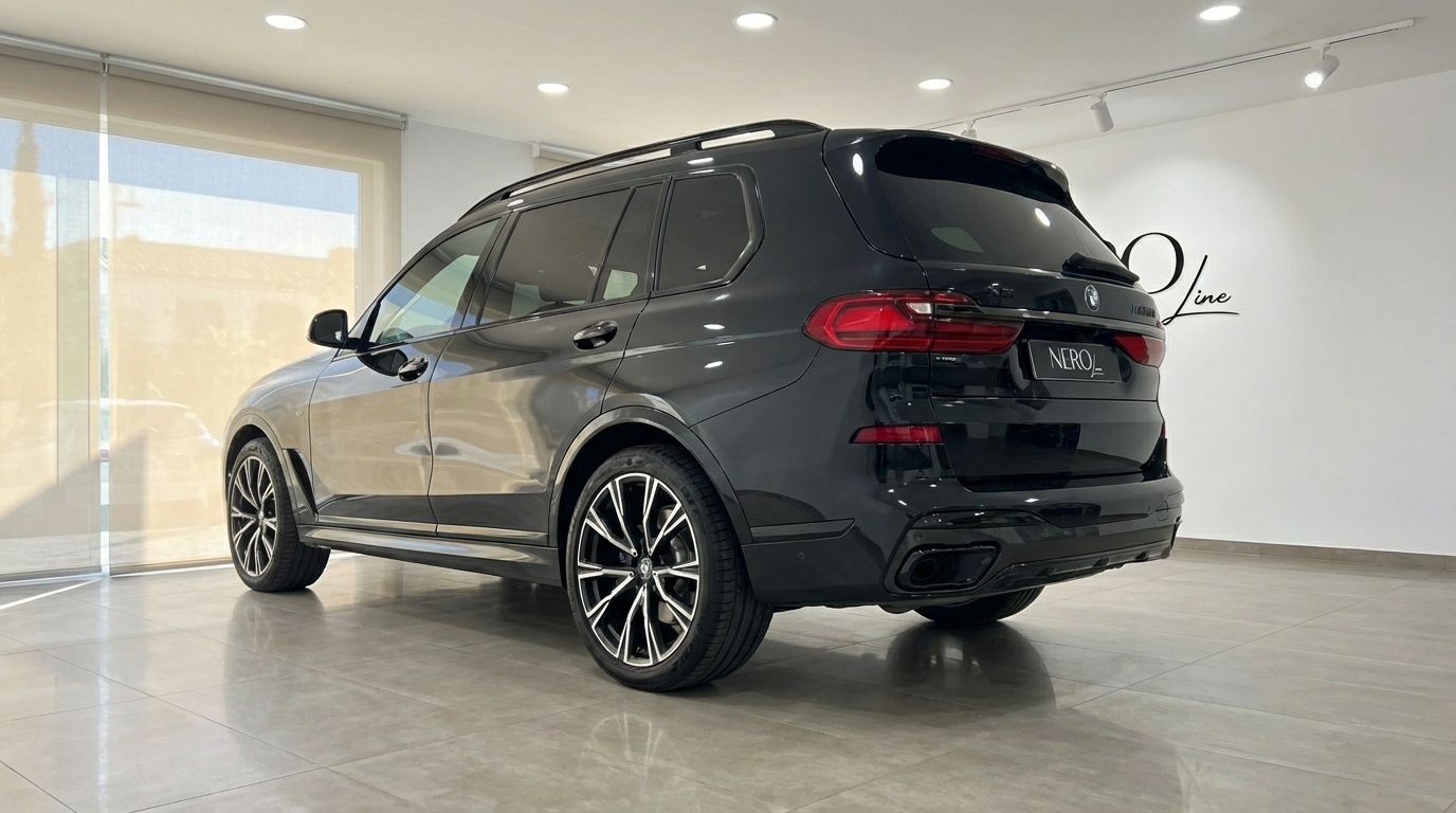 The black 2025 BMW X7 M50i Special Edition is shown from a rear three-quarter angle inside a showroom in Alicante.