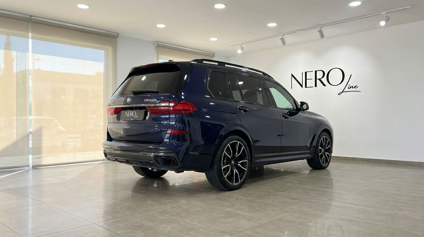 El BMW X7 M60i azul oscuro de 2024 se muestra desde un ángulo trasero tres cuartos en una sala de exposición en Madrid.