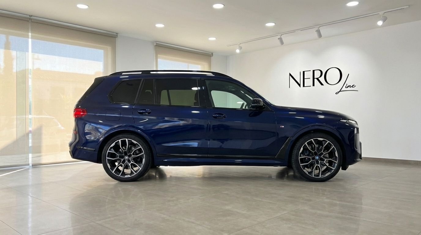 El SUV de lujo y rendimiento BMW X7 M60i 2024 azul oscuro se muestra de perfil dentro de un concesionario en Madrid.