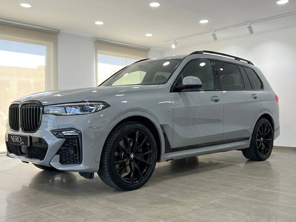 BMW X7 xDrive M Sport — Front three-quarter view The grey BMW X7 xDrive M Sport, featuring black wheels, is showcased from a front three-quarter view indoors in Marbella.