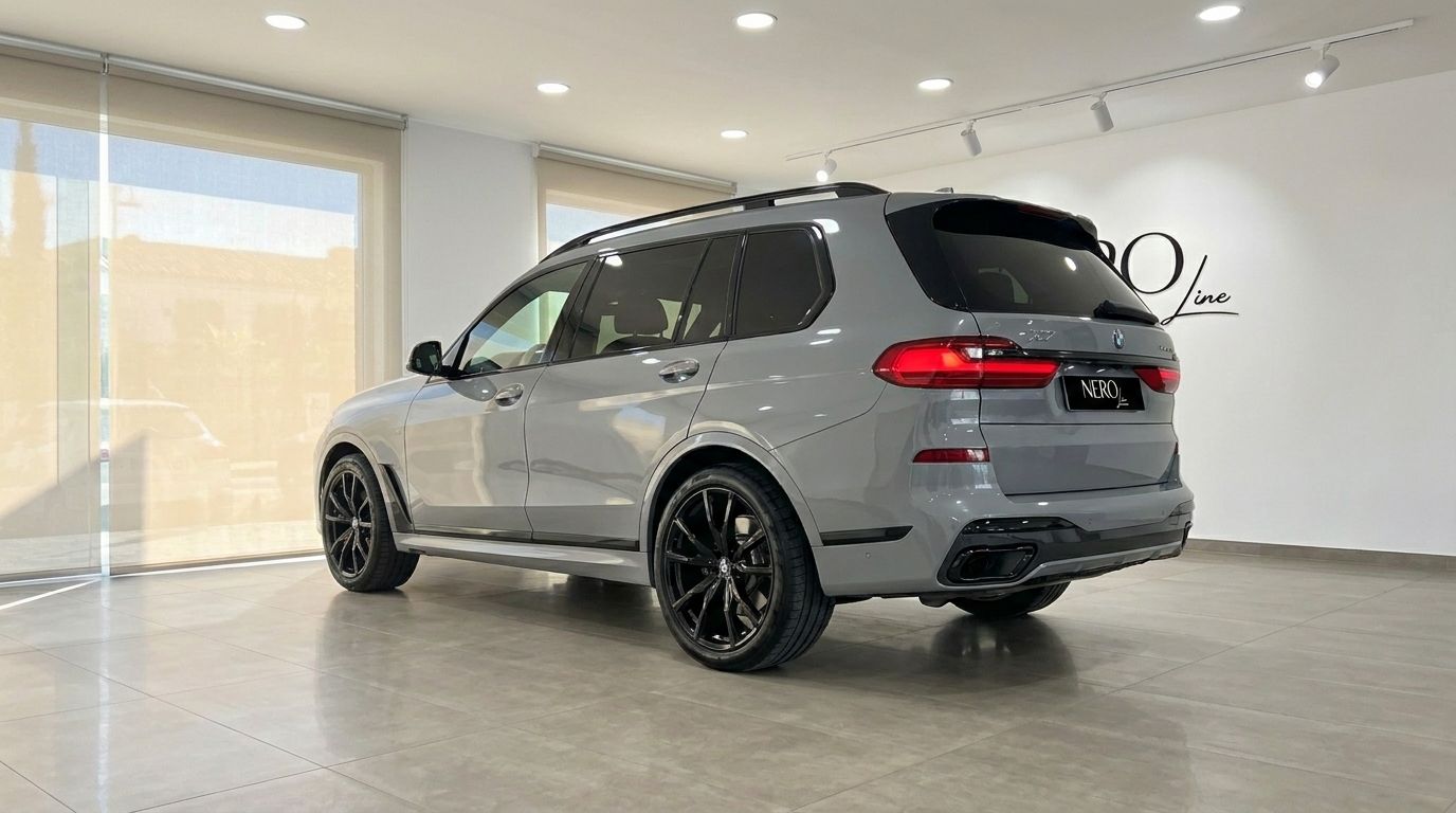 The Gloss Brooklyn Grey BMW X7 xDrive M Sport SUV is showcased from a rear-three-quarter view in a Marbella showroom.