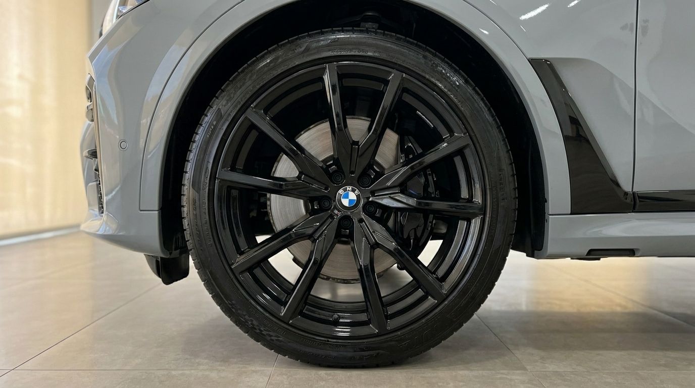 Close-up of the black multi-spoke front wheel and Gloss Brooklyn Grey fender of the BMW X7 xDrive M Sport in Marbella.