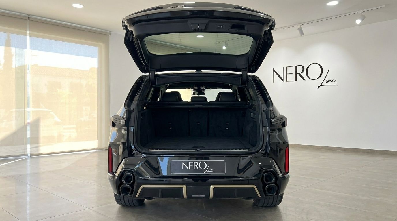 The black 2025 BMW XM is shown from the rear with its trunk open, revealing the spacious cargo area in Alicante.
