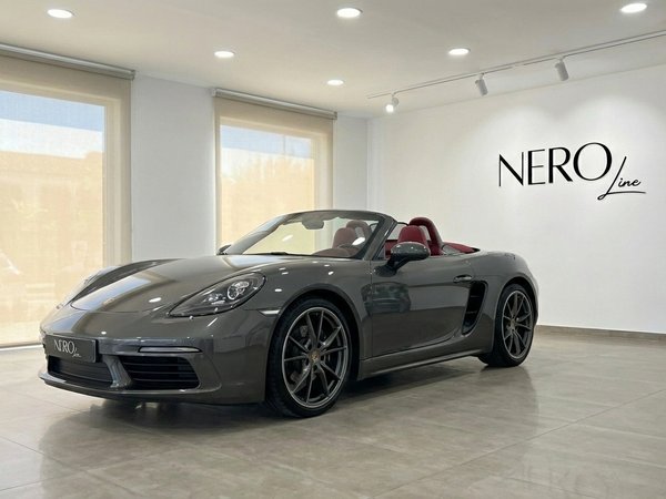 Porsche 718 Boxster S — Luxury Sports Convertible A metallic grey 2019 Porsche 718 Boxster S convertible with a red interior, shown from the front three-quarter angle in Barcelona.