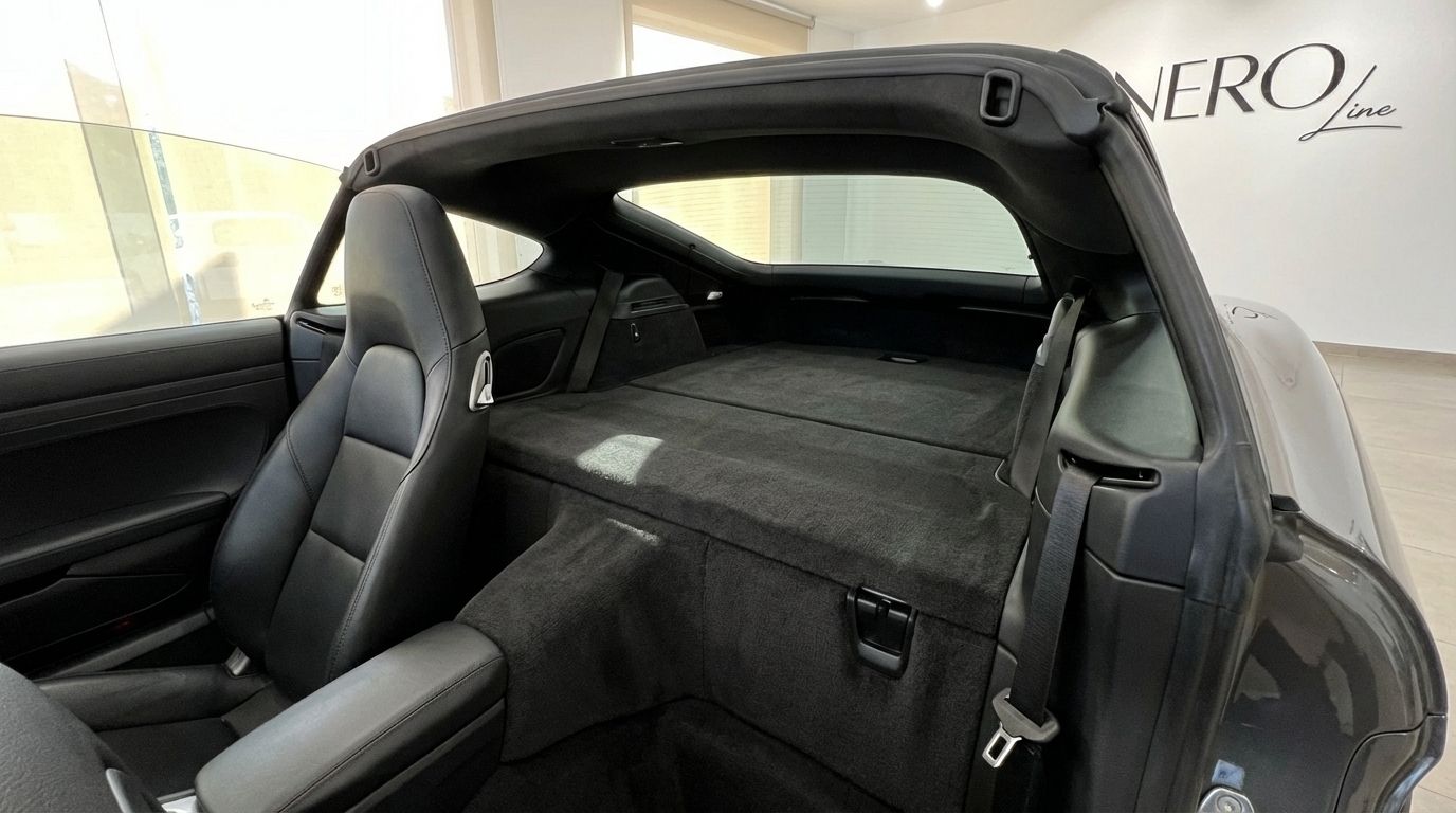 Porsche 718 Boxster S interior showing the black leather passenger seat and the carpeted rear storage area in Barcelona.