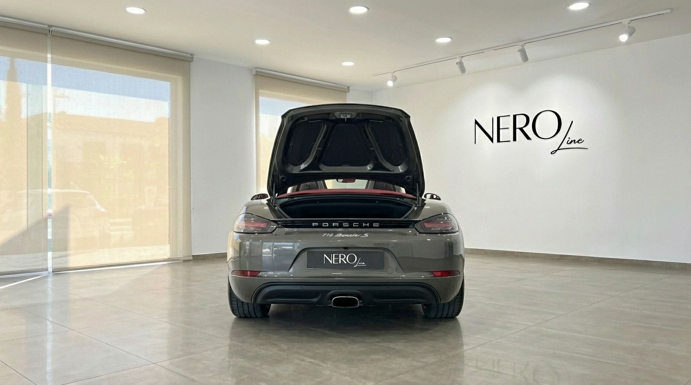 The metallic grey Porsche 718 Boxster S, with its trunk open, is parked in a showroom in Barcelona.