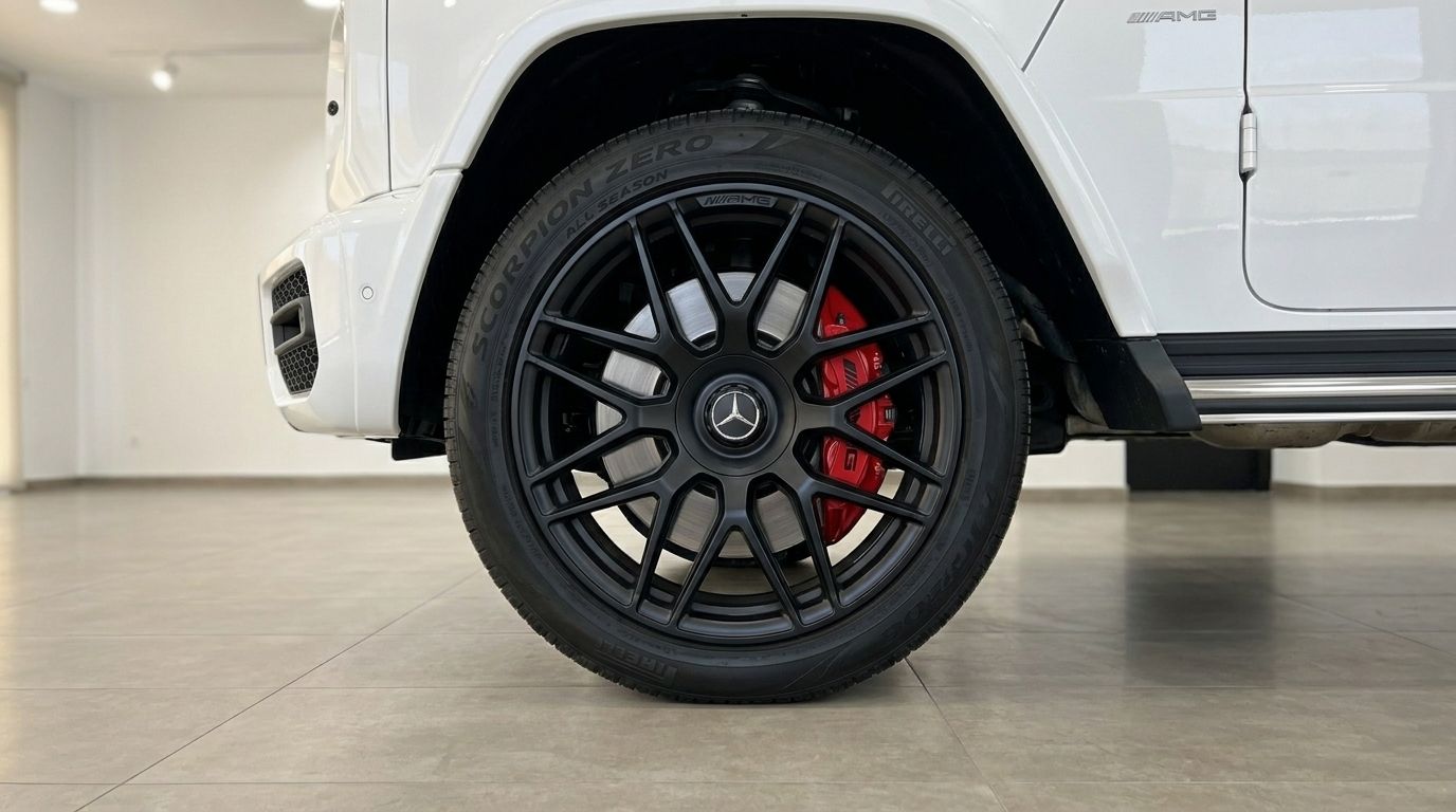 لقطة مقربة للعجلة الأمامية لسيارة مرسيدس-AMG G 63، تعرض الجنط الأسود متعدد الأضلاع ومكابح الفرامل الحمراء في ماربيا.