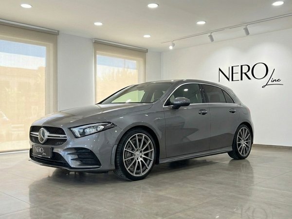 Mercedes-Benz A 45 AMG — Luxury Car Rental Alicante The metallic grey 2022 Mercedes-Benz A 45 AMG is showcased from a front three-quarter view in a showroom in Alicante.