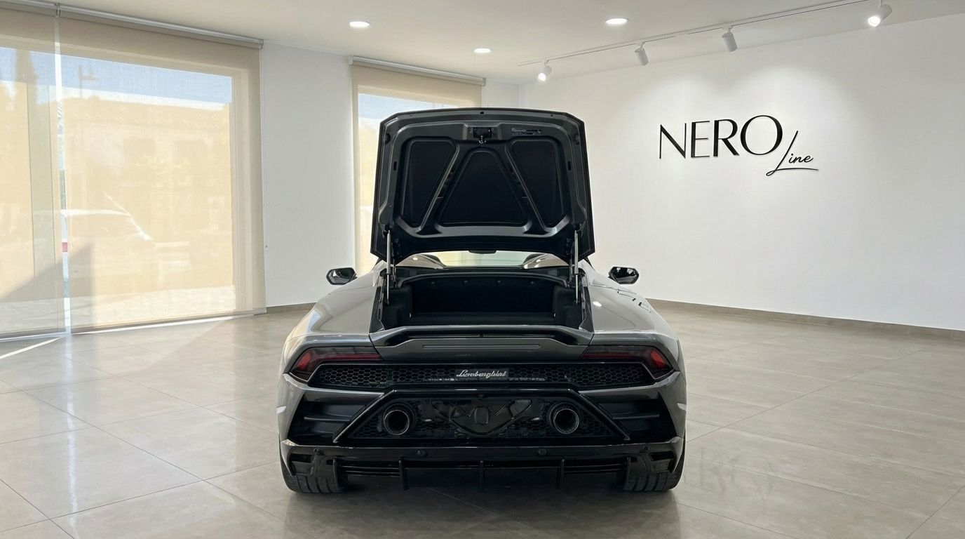 The rear view of a metallic grey Lamborghini Huracan Evo Spyder with its trunk open, parked in a showroom in Barcelona.