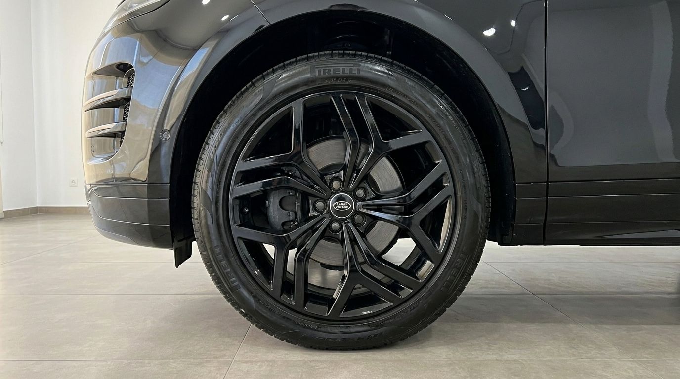 The glossy black front wheel and tire of the Land Rover Range Rover Evoque R-Dynamic (2nd) are visible, along with part of its sleek black bodywork, in Alicante.