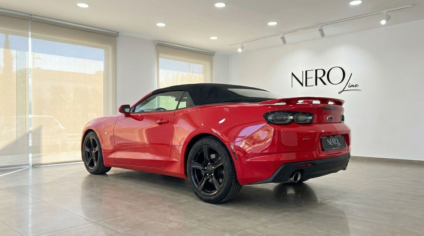 O Chevrolet Camaro conversível vermelho de 2020 está estacionado dentro, exibindo sua elegante vista traseira três quartos em Alicante.
