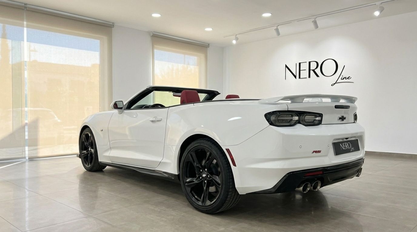 The white Chevrolet Camaro Cabrio 3.6, with its red interior, is showcased from a rear three-quarter angle in a showroom in Alicante.