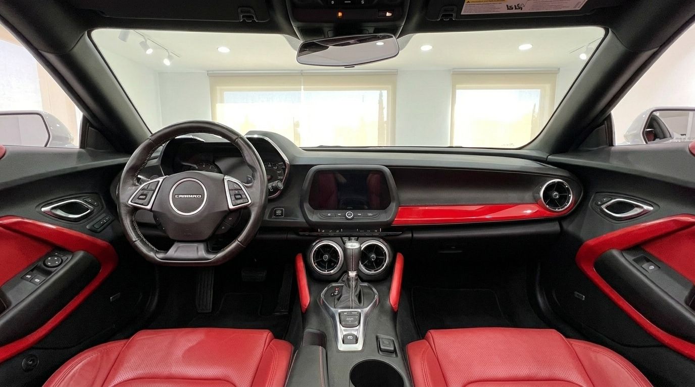 The interior of the Chevrolet Camaro Cabrio 3.6 in Alicante features a black and red dashboard, steering wheel, and luxurious red leather seats.