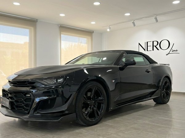 Chevrolet Camaro Cabriolet — Showroom ad Alicante L'elegante Chevrolet Camaro Cabriolet nera è esposta da un'angolazione anteriore-laterale in un moderno showroom ad Alicante.