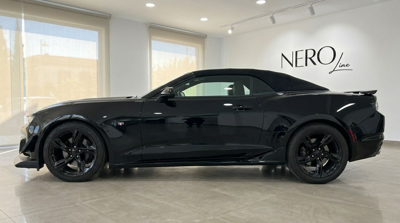 O elegante Chevrolet Camaro Cabriolet preto de 2021 é exibido em vista lateral completa dentro de um moderno showroom em Alicante.