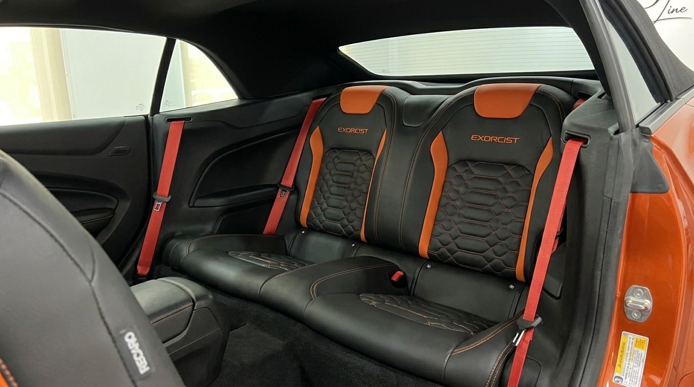 The rear black and orange leather seats with red seatbelts in the Chevrolet Camaro Cabriolet 6.2 interior, available in Alicante.