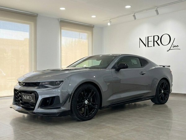 Chevrolet Camaro — Front three-quarter view, Alicante The sleek grey 2020 Chevrolet Camaro is showcased in a front three-quarter view within a bright showroom in Alicante.