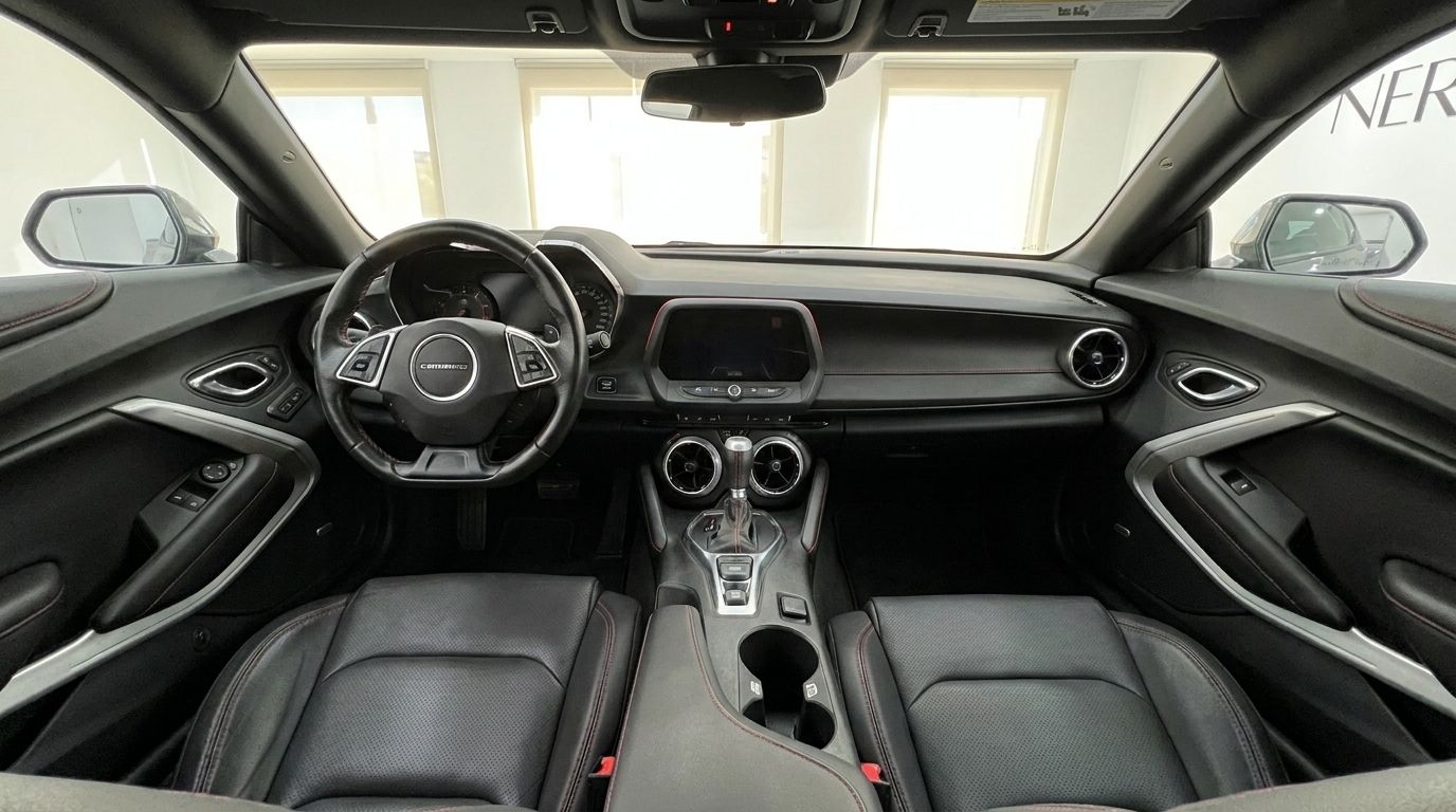 O interior do Chevrolet Camaro 2020 em Alicante apresenta um painel preto, volante e bancos dianteiros de couro com costuras vermelhas.