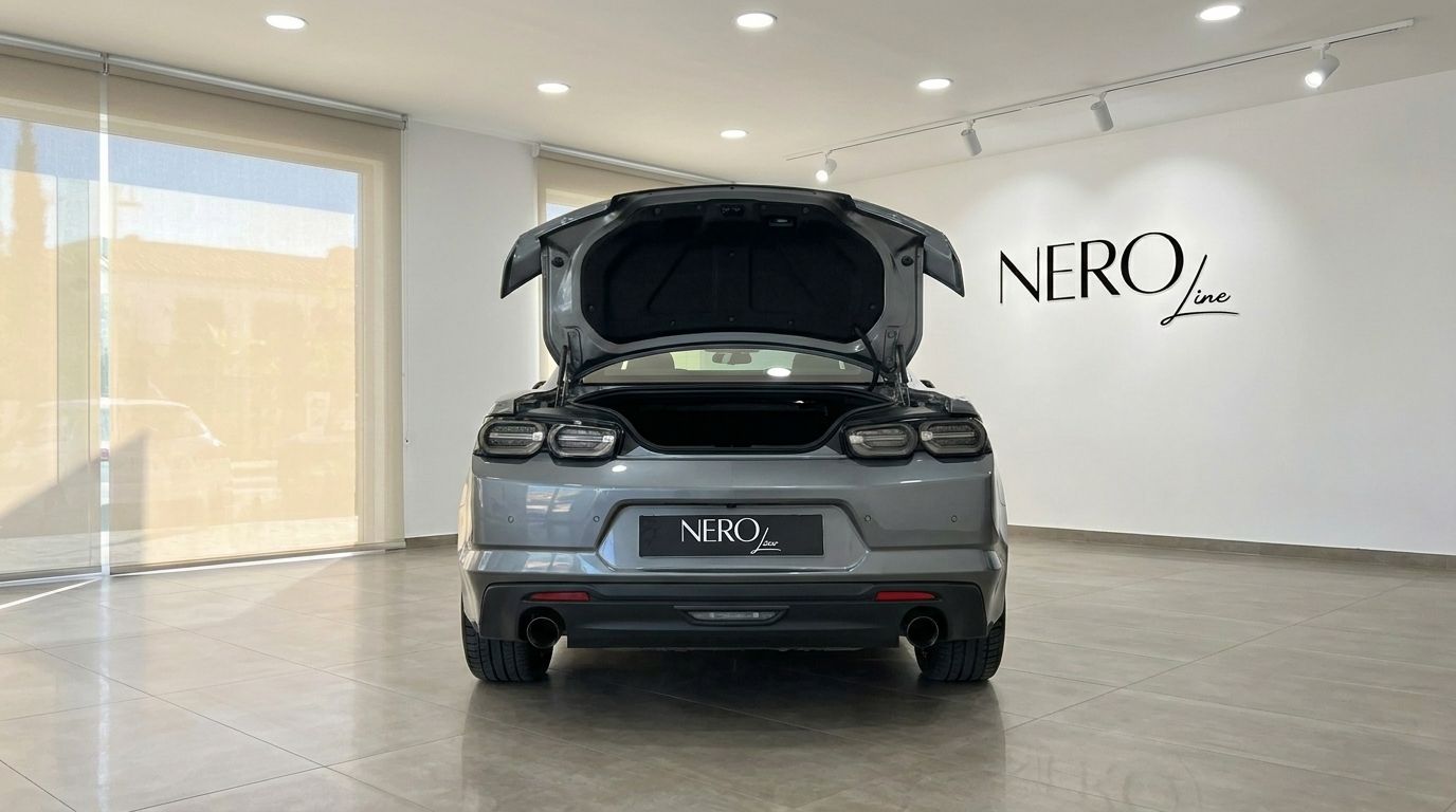 O Chevrolet Camaro 2020 cinzento é mostrado de traseira com a bagageira aberta, estacionado num showroom em Alicante.