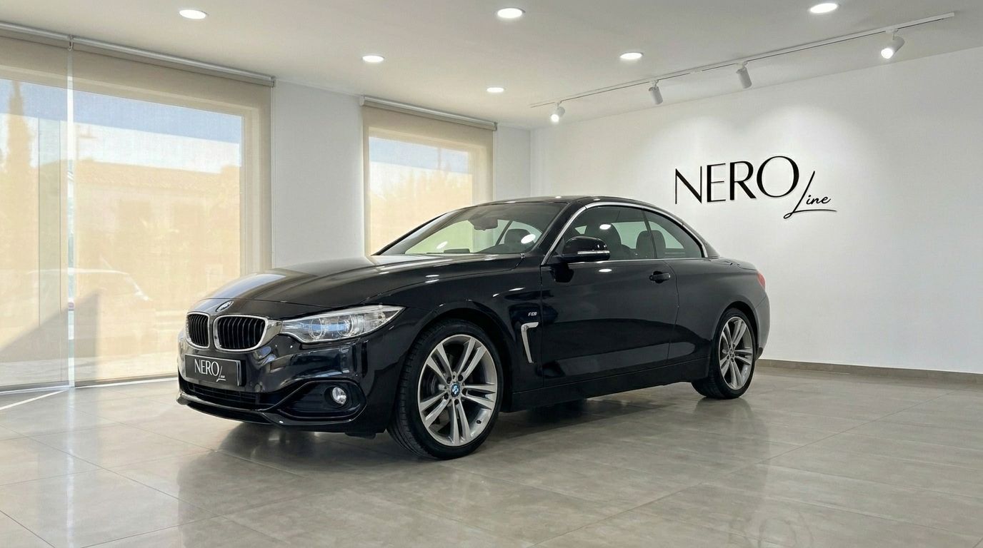 The black BMW 420 Cabriolet, with its hardtop up, is showcased from a front-three-quarter angle in a modern Alicante showroom.