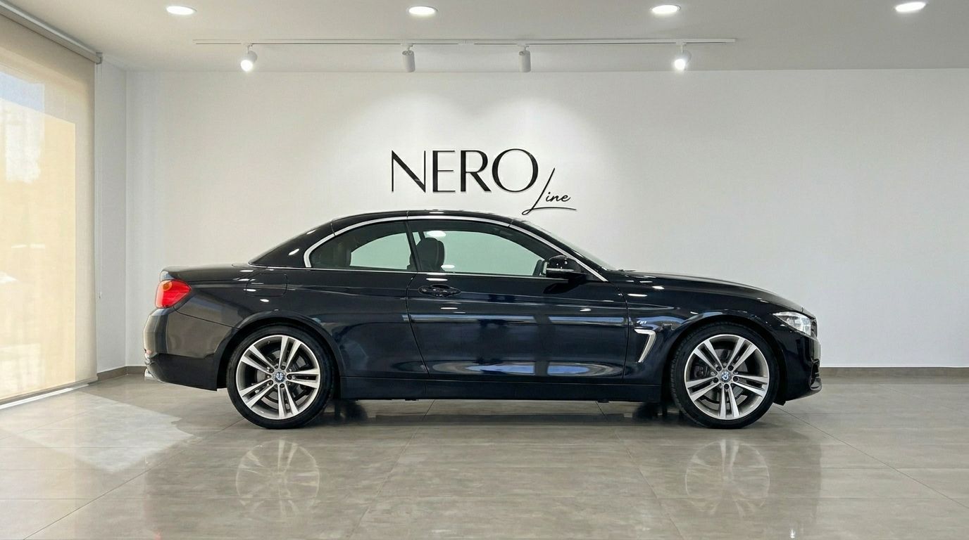 The black 2017 BMW 420 Cabriolet is shown from its side profile, parked with its hardtop up in a modern showroom in Alicante.