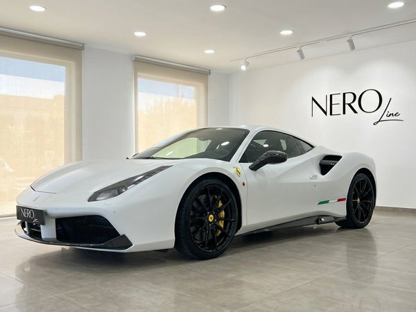 Ferrari 488 GTB — Présentation en showroom Madrid Une Ferrari 488 GTB blanche mate est présentée de trois quarts avant dans un showroom moderne avec le logo Nero Line à Madrid.