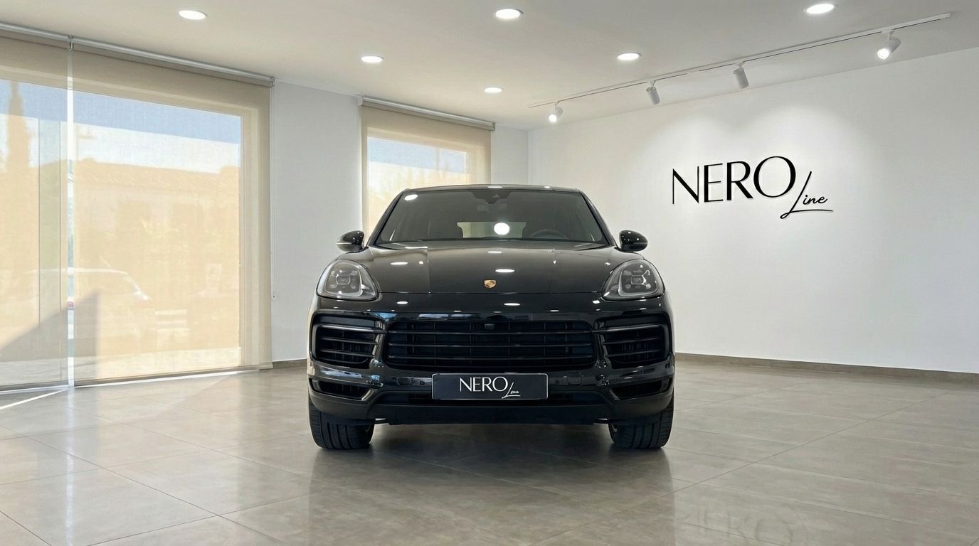 The black 2025 Porsche Cayenne Coupe is prominently displayed from the front in a bright showroom in Marbella.