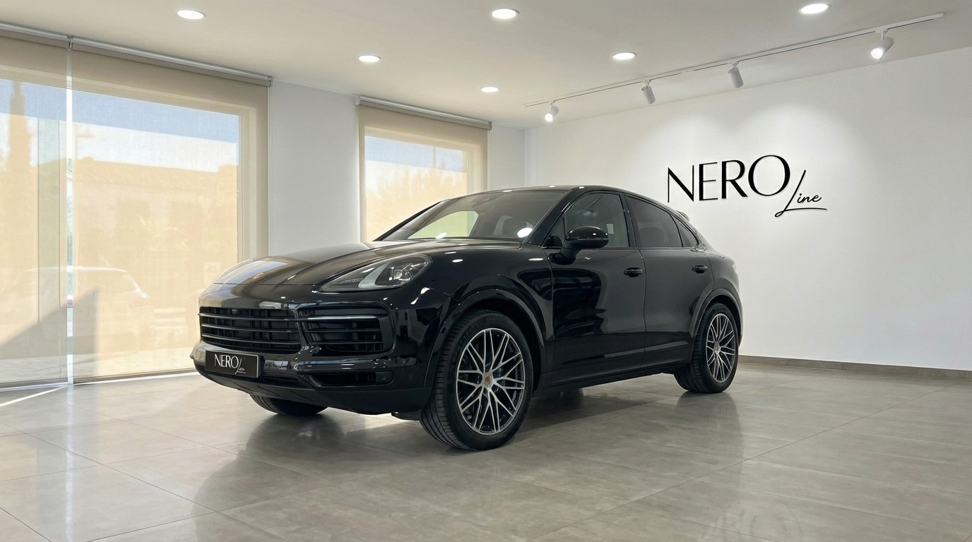 Porsche Cayenne Coupe — Showroom Marbella A sleek black 2025 Porsche Cayenne Coupe is displayed from a front three-quarter angle inside a modern showroom in Marbella.