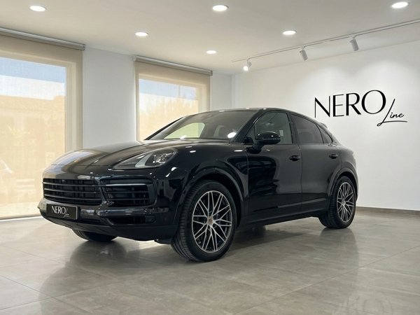 Porsche Cayenne Coupe — Showroom Marbella A sleek black 2025 Porsche Cayenne Coupe is displayed from a front three-quarter angle inside a modern showroom in Marbella.
