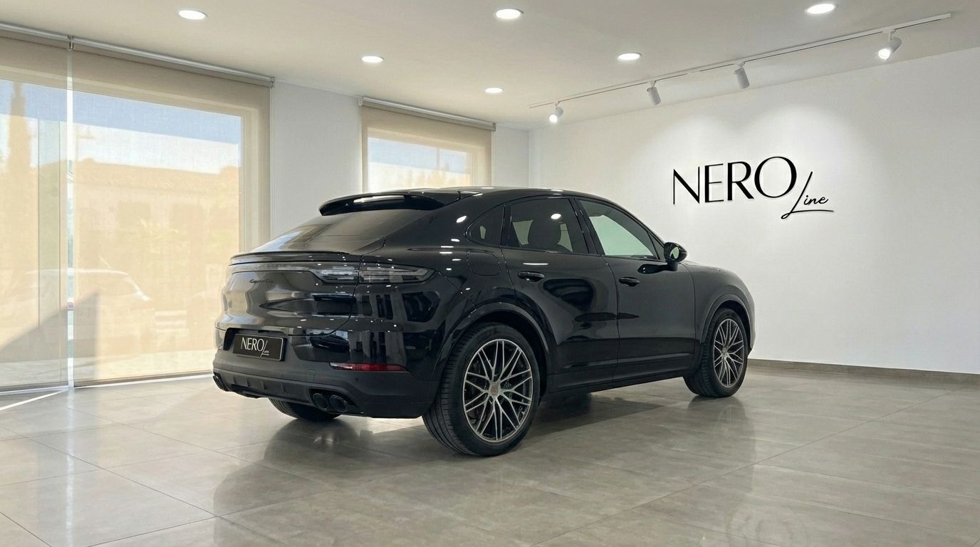 The black 2025 Porsche Cayenne Coupe is showcased from a rear three-quarter angle in a Marbella showroom.