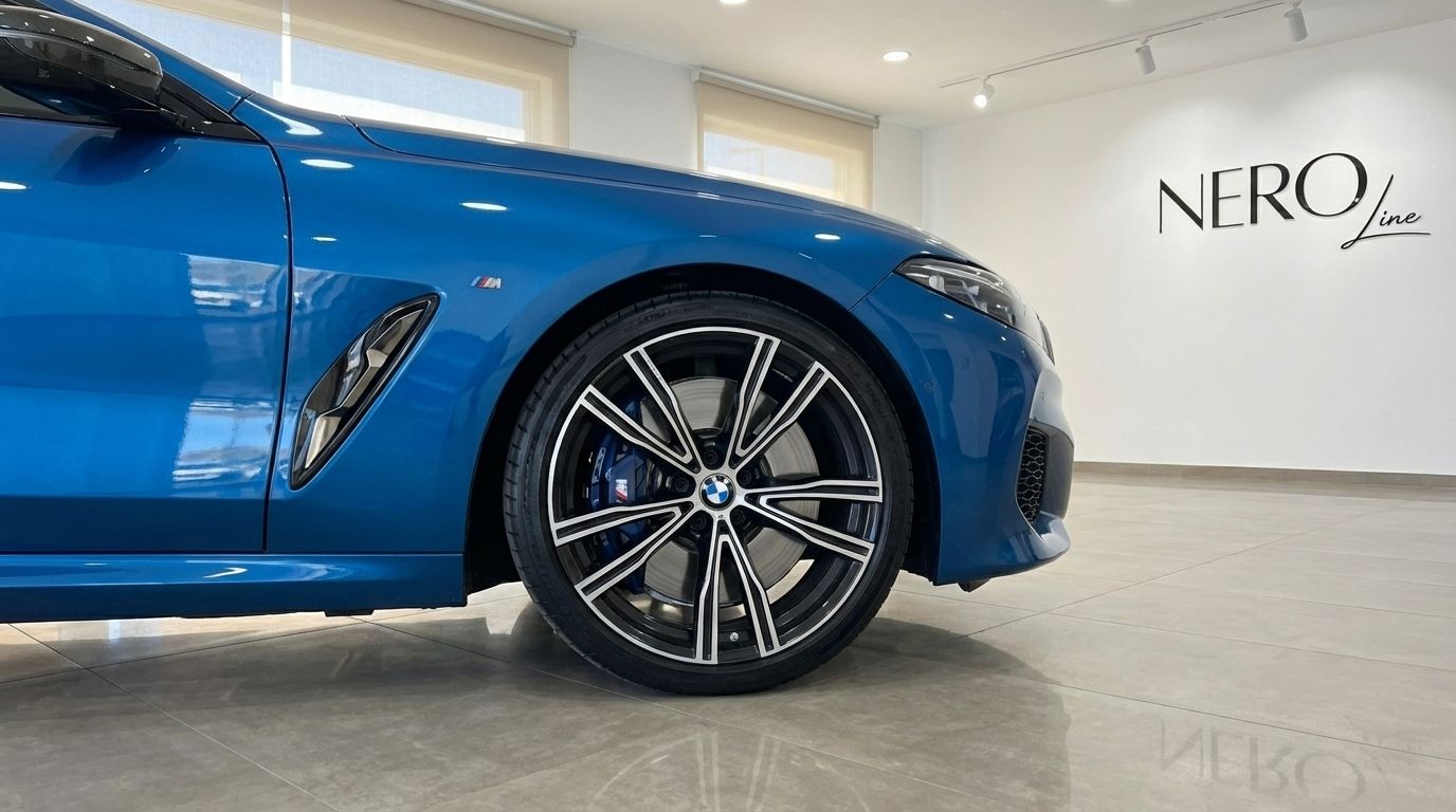 The front-right wheel and side panel of the sky blue BMW M850i Carbon Core Edition, featuring its multi-spoke rim and M brake caliper in Alicante.