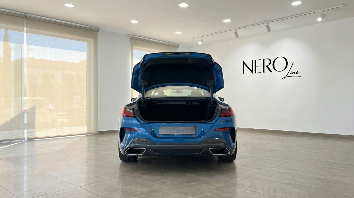 The rear of a sky blue BMW M850i Carbon Core Edition with its trunk open, displayed in a showroom in Alicante.