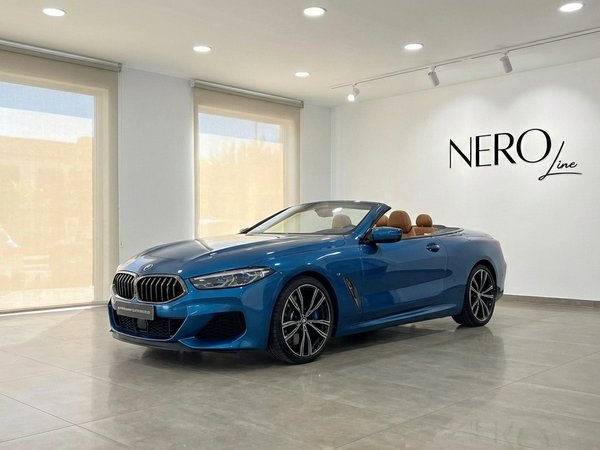 BMW M850i Carbon Core Edition — Showroom Alicante The sky blue BMW M850i Carbon Core Edition convertible with its top down and tan interior is displayed in a showroom in Alicante.