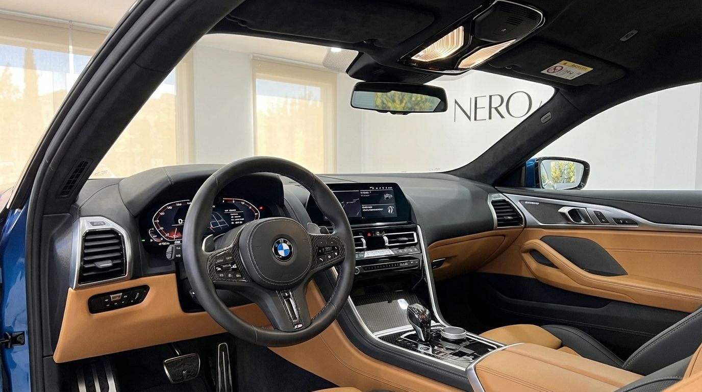 The luxurious interior cockpit of the BMW M850i Carbon Core Edition in Alicante, featuring a leather steering wheel and tan dashboard.