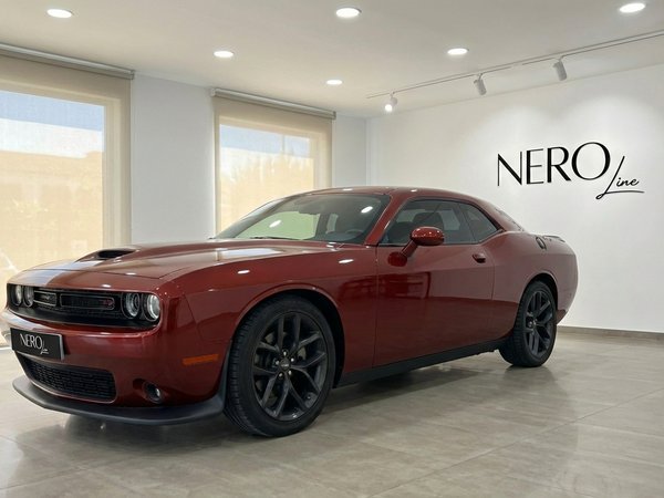 Dodge Challenger V6 — Showroom view in Alicante The burnt orange 2023 Dodge Challenger V6 is showcased from a front three-quarter angle in a bright Alicante showroom.