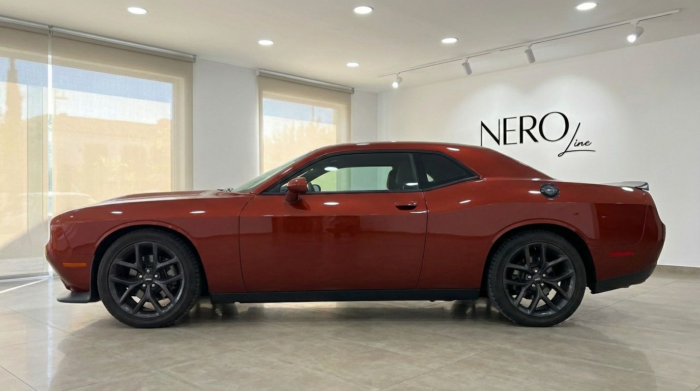 The burnt orange 2023 Dodge Challenger V6 is shown in a side profile view within a showroom in Alicante.