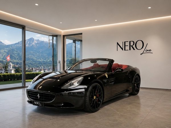 Ferrari California T — Showroom view in Zurich A black Ferrari California T convertible with red interior parked in a modern showroom, overlooking the mountains and a town in Zurich.