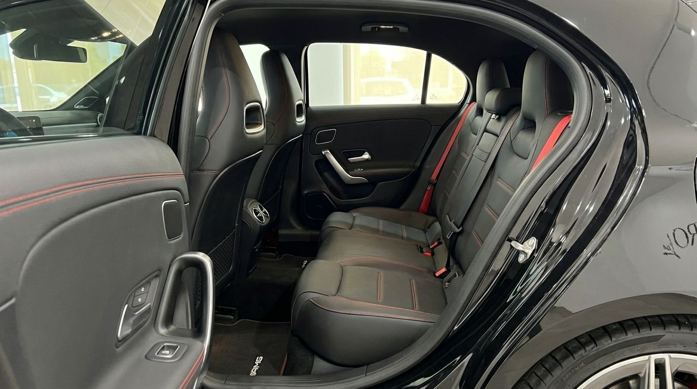 View of the Mercedes-Benz A 45 S rear interior in Alicante, featuring black leather seats with red stitching and an open door.
