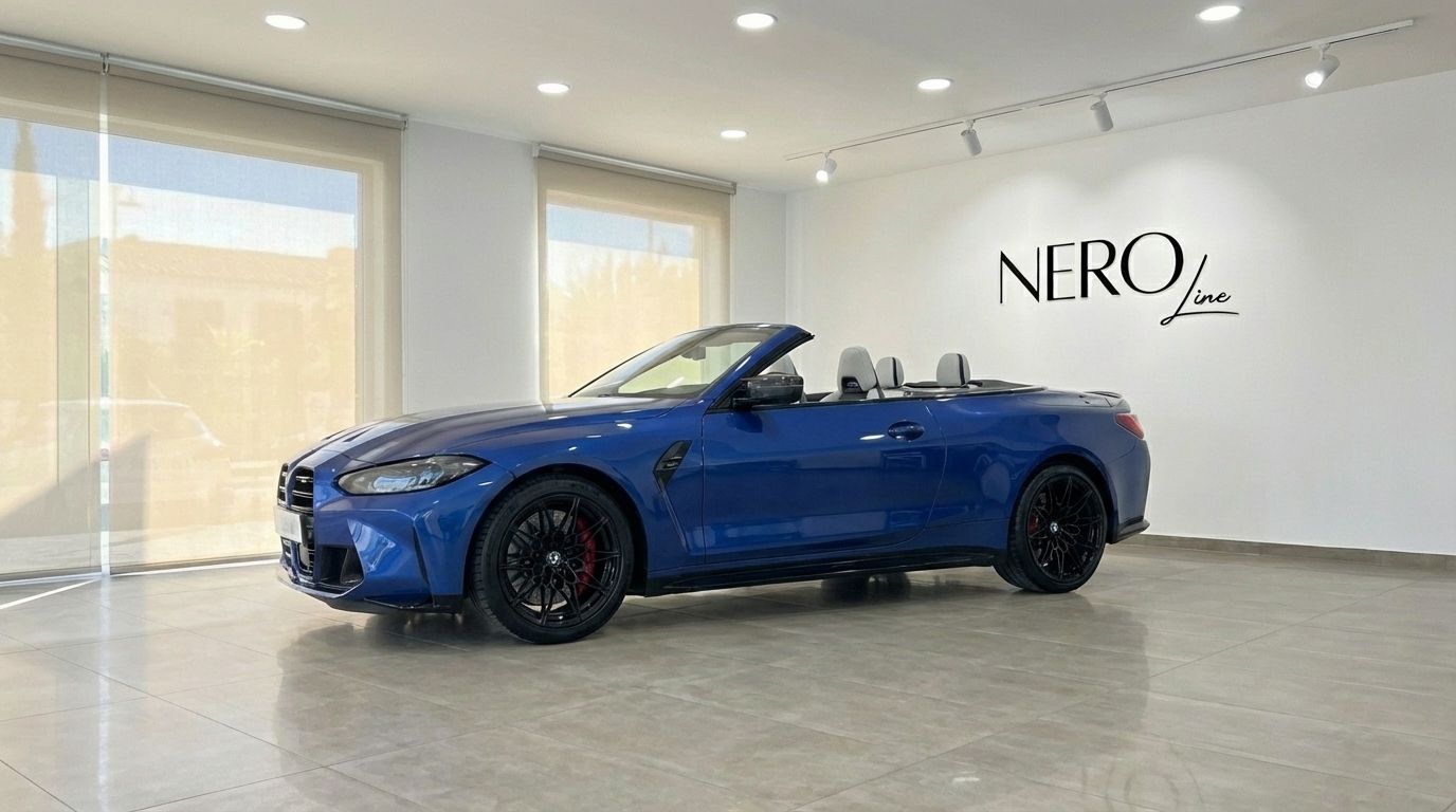 The metallic blue BMW M4 Competition Convertible is showcased from a side-front angle in a Barcelona showroom.