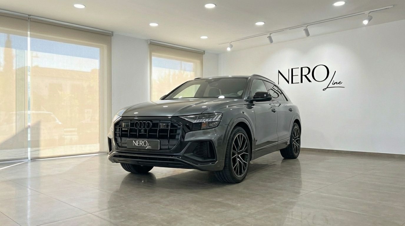 The matte gray Audi Q8 TDI is showcased in a showroom, captured from a front three-quarter view in Alicante.